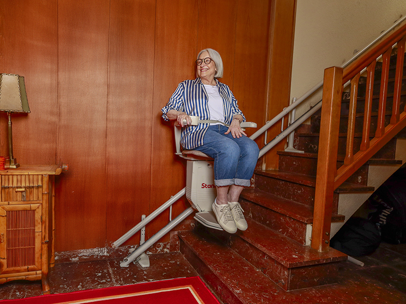 Mujer mayor usa una silla salvaescaleras Stannah y se siente feliz e independiente
