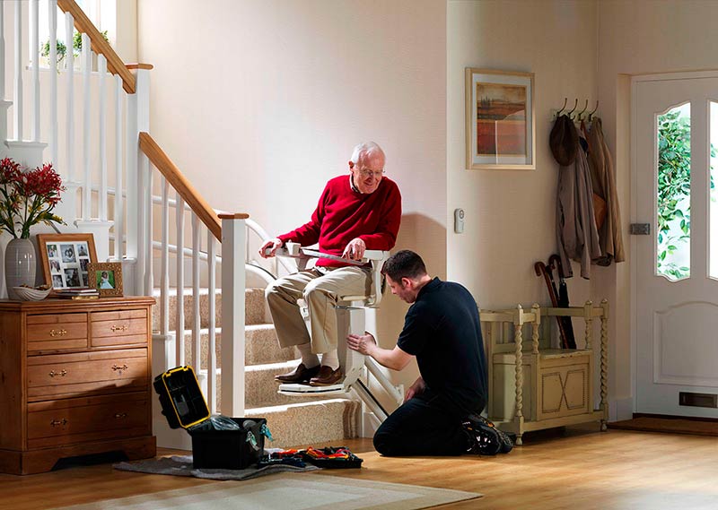 Técnico de instalación instalando silla salvaescaleras con cliente